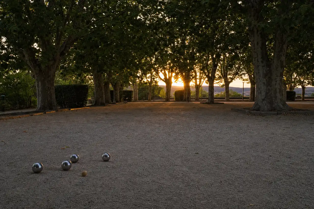 Boulodrome de pétanque sous les platanes, boules et cochonnet sur le gravier